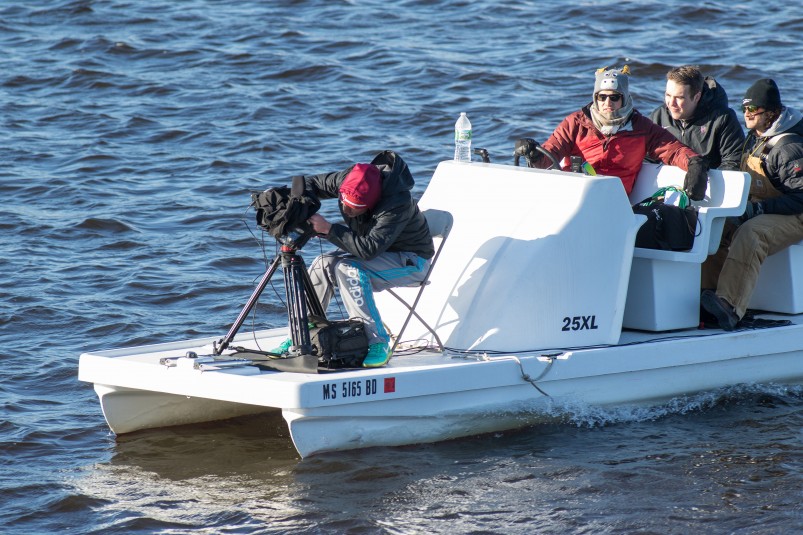 Harvard’s rowing-production boat carries a driver, a camera operator, and two commentators and weather-protected gear.
